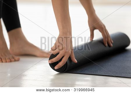 Young Woman Rolling Black Yoga Mat, Hands Close Up