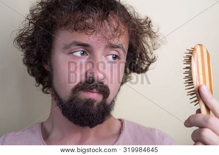 Portrait Of A Young Guy With Long Dirty Hair And Problematic Scalp. Holding A Comb With Fallen Hair