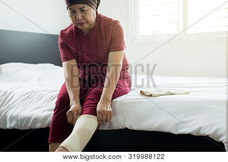 Senior Asian Woman Using Elastic Bandage With Leg,female Putting Bandage On Her Injured Knee
