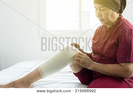 Elderly Asian Woman Using Elastic Bandage With Leg,female Putting Bandage On Her Injured Knee