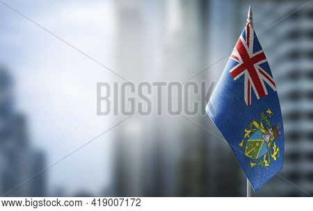 A Small Flag Of Pitcairn Islands On The Background Of A Blurred Background