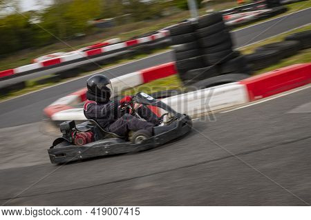 A Panning Shot Of A Racing Kart As It Circuits A Track.