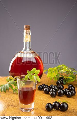 Jaboticaba, Bottle And Glass Of Homemade Brazilian Jaboticaba Liqueur On Wood With Leaves And Branch