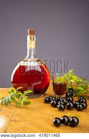 Jaboticaba, Bottle And Glass Of Homemade Brazilian Jaboticaba Liqueur On Wood With Leaves And Branch