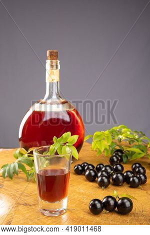 Jaboticaba, Bottle And Glass Of Homemade Brazilian Jaboticaba Liqueur On Wood With Leaves And Branch