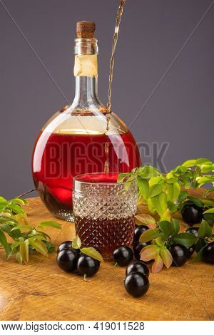 Jaboticaba, Bottle And Glass Of Homemade Brazilian Jaboticaba Liqueur On Wood With Leaves And Branch