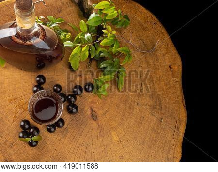 Jaboticaba, Bottle And Glass Of Homemade Brazilian Jaboticaba Liqueur On Wood With Leaves And Branch