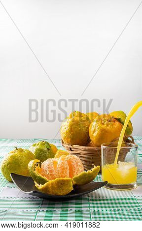 Orange Ponkan, Orange Ponkan Open On A Black Plate, Plus Some Oranges And A Glass Of Juice On A Chec