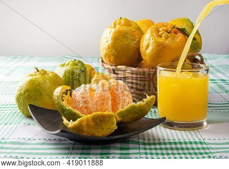 Orange Ponkan, Orange Ponkan Open On A Black Plate, Plus Some Oranges And A Glass Of Juice On A Chec