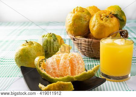 Orange Ponkan, Orange Ponkan Open On A Black Plate, Plus Some Oranges And A Glass Of Juice On A Chec