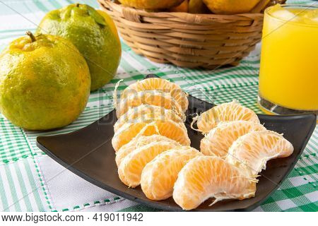 Orange Ponkan, Orange Ponkan Slices On A Black Plate, Plus Some Oranges And A Glass Of Juice On A Ch