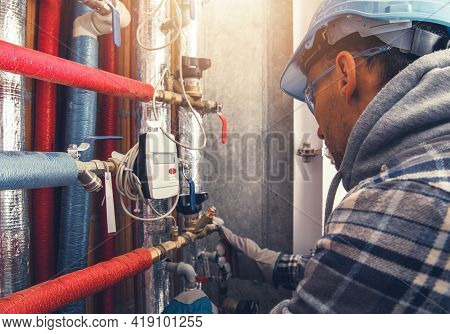Hvac Heating Technician Making Final Check Of The System. Checking All Hot Water Valves, Pipelines A