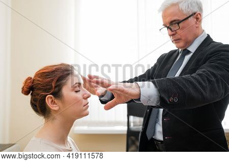 Mature Gray-haired Man Hypnotizes Caucasian Woman During Hypnotherapy Session. The Psychologist Uses