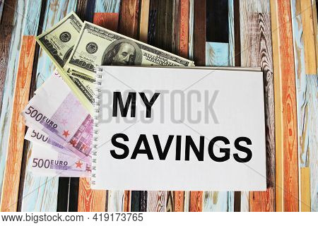 Text My Savings Written On A Notepad, Next To Euro And Dollar Banknotes On A Striped Background, The