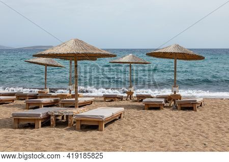 View Of Sandy Soros Beach On The Greek Island Of Antiparos With Sunbeds And Umbrellas. Cloudy Day.