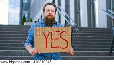 Portrait Shot Of Caucasian Male Activist With Beard Holding Poster Yes At Demonstration Or Protest. 
