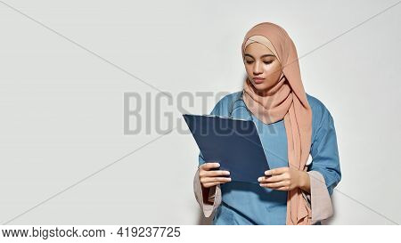 Young Arabian Woman Doctor With Stethoscope Looking Into Notepad While Posing On Light Background Wi