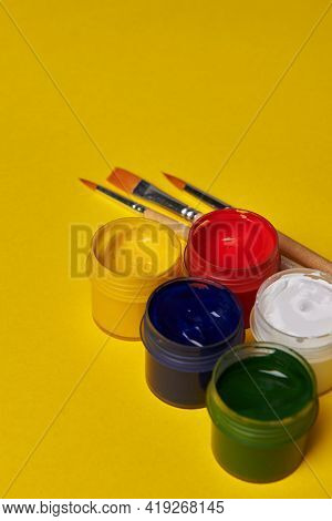 Colored Jars Of Paint On A Yellow Background