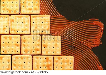Crackers And Chocolate Paste On Black Background, Cookies Lined Up Like Brickwork Or Ceramic Tiles, 