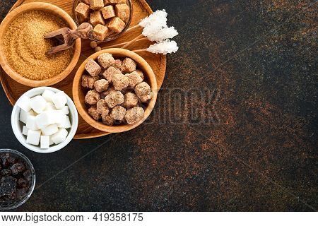 White Sugar, Cane Sugar Cubes, Caramel In Bamboo Bowl On Dark Brown Table Concrete Background. Assor