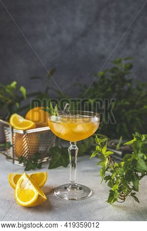 Champagne Coupe Glass Of Refreshing Orange Cocktail With Ice Served On Gray Table Surface Surround O