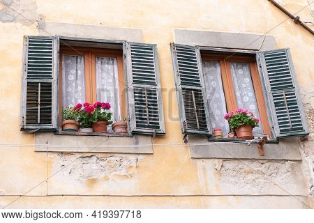 Old Windows In A Medieval Town. Windows With Street Sills With Flowers On Them. The Old Italian Shut