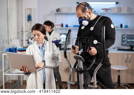 Man Athlete Running On Cross Trainer With Electrodes Attached