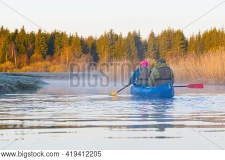 Retirees Rowing A Canoe In Early Spring In The Early Morning. Seniors Lifestyle. Morning Landscape, 