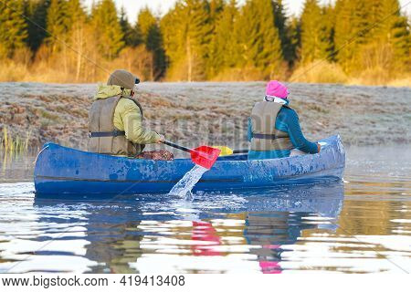 Retirees Rowing A Canoe In Early Spring In The Early Morning. Seniors Lifestyle. Morning Landscape, 