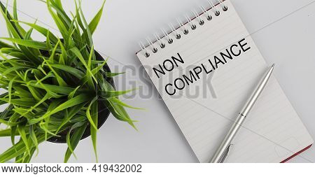 Keyword Non Compliance - Business Concept Text On White Notebook And Pen, Green Flowers