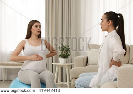 Doula Working With Pregnant Woman In Living Room. Preparation For Child Birth