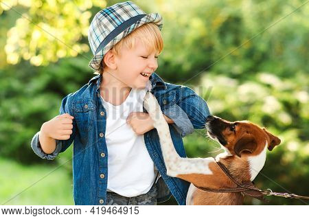Happy Child Having Fun Together With Dog Outdoors. Little Puppy Jack Russel Terrier Playing With Boy