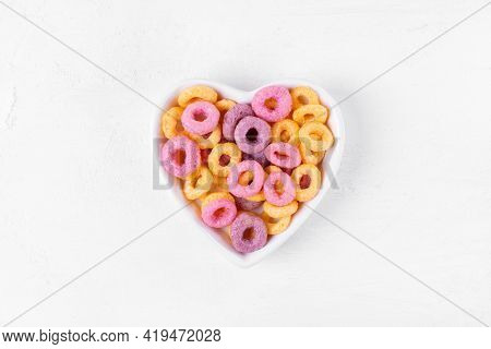 Multicolored Breakfast Cereal Loops In Heart Shaped Bowl On The White Table