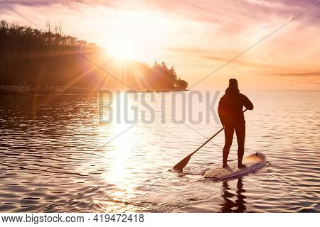 Adventurous Girl On A Paddle Board Is Paddeling In The Pacific West Coast Ocean. Sunset Sky Art Rend