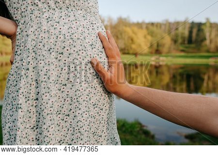 The Man Holds His Hand On The Belly Of A Pregnant Woman