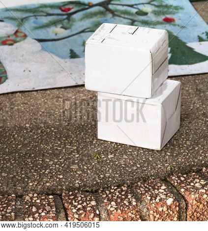 Two Small White Packages Delivered To A Front Stoop Left Out Exposed To The Elements And Thieves.