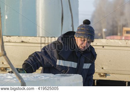 Slinger In A Blue Jacket Unloading Ice Blocks