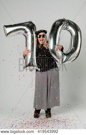 Senior woman holding silver balloons for 10 years celebration