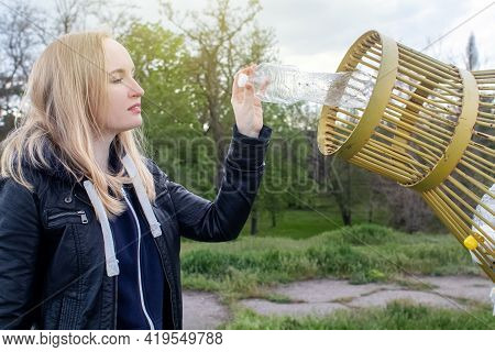 A Woman Tosses A Plastic Bottle Into A Plastic Container For Collection. Recycling And Disposal Of P