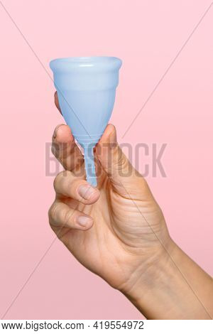 Hand holding blue menstrual cup