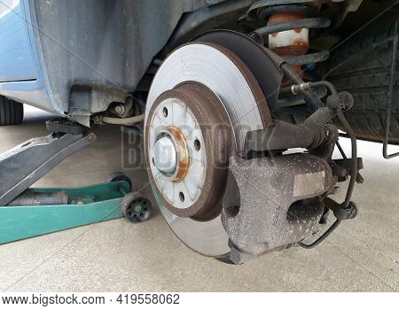 Close Up Of A Car Disc Brake And A Jack During Car Maintenance. Close Up Of Disc Brake Without The W