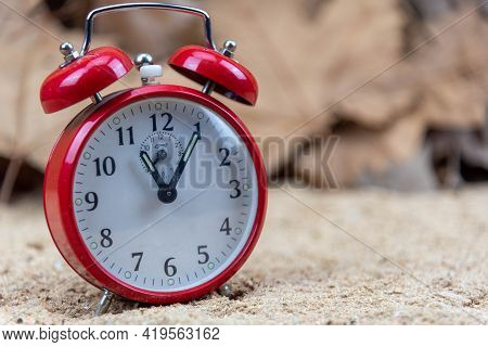 Red Analog Clock And Maple Leaves In The Background