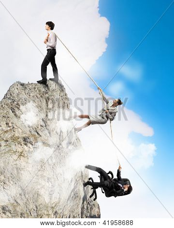 Imagem de três empresários puxando a corda no topo da montanha