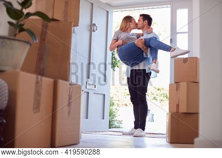 Man Carrying Woman Over Threshold Of New Home As Couple Move In Together