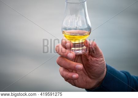Hand With Dram Of Single Malt Scotch Whisky On Seashore In Scotland