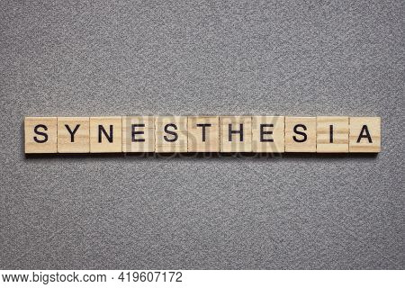 Text The Word Synesthesia From Brown Wooden Small Letters With Black Font On An Gray Table