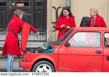 Cesis, Latvia - May 02, 2021: Three Women In Red Clothes At A Red Vintage Car Fiat 126 With An Open 
