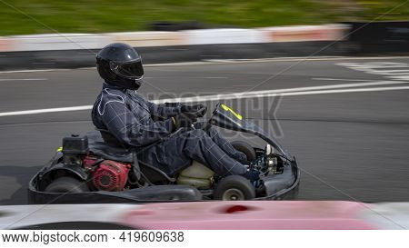A Panning Shot Of A Racing Kart As It Circuits A Track.