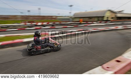 A Panning Shot Of A Racing Kart As It Circuits A Track.