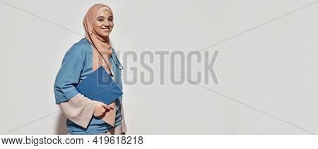 Smiling Young Arabian Woman Doctor In Hijab Holding Notepad While Posing On Light Background With Co